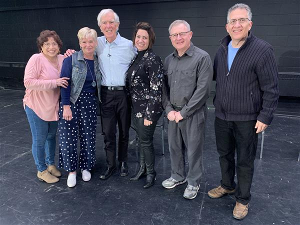 The group of alumni and Bob Sagan pose onstage during a visit
